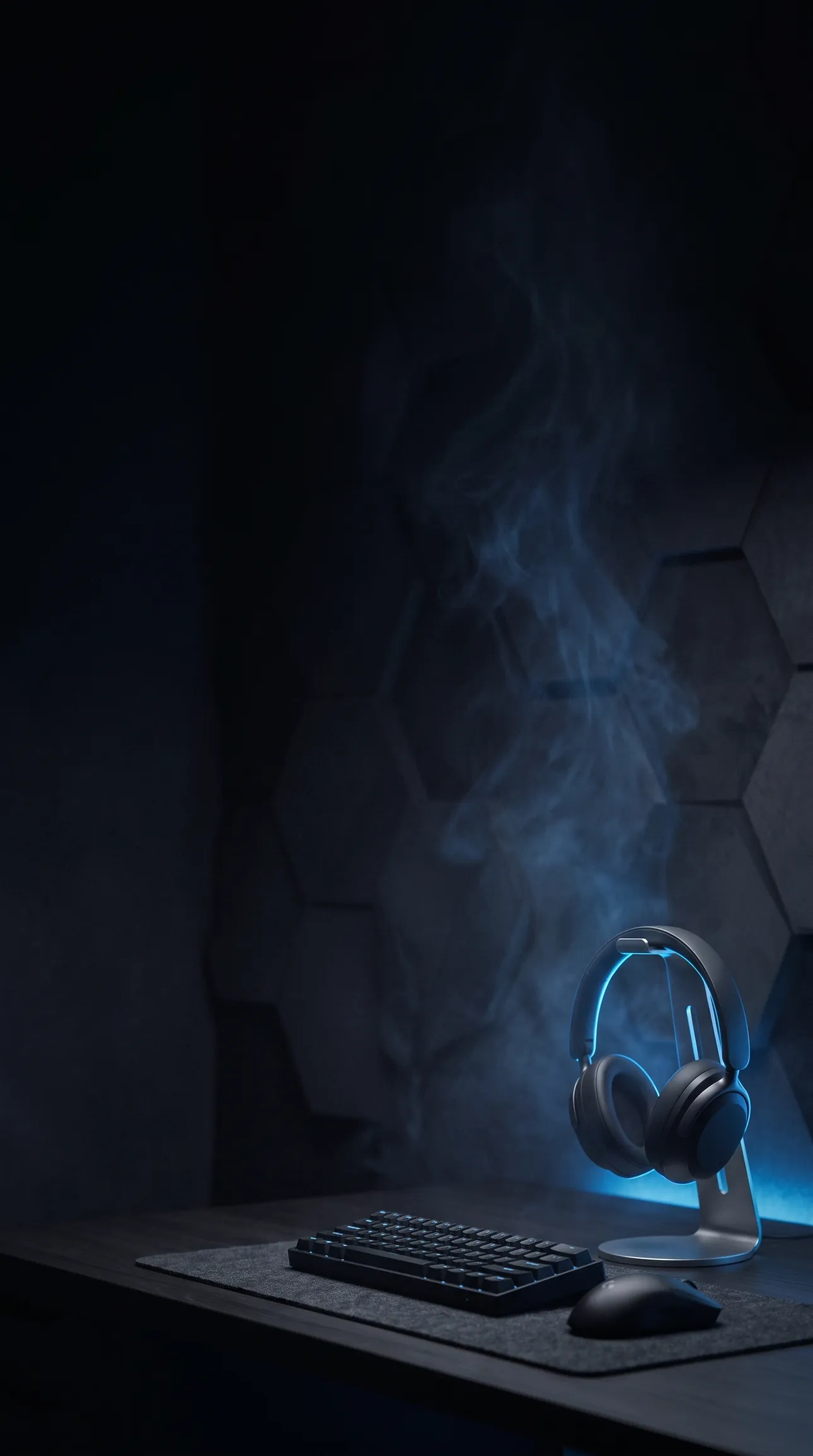 Headphones on a stand beside a compact keyboard and mouse, lit by a soft blue glow on a dark desk